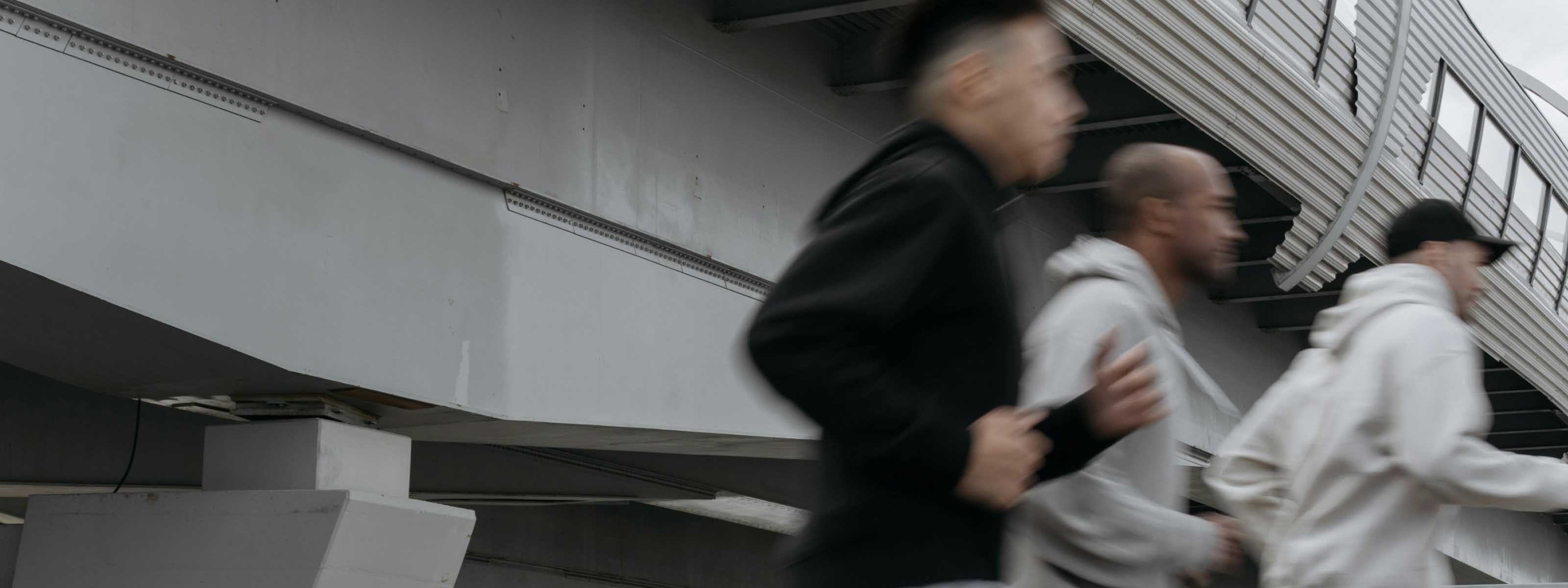 Three men in motion, jogging underneath an overpass