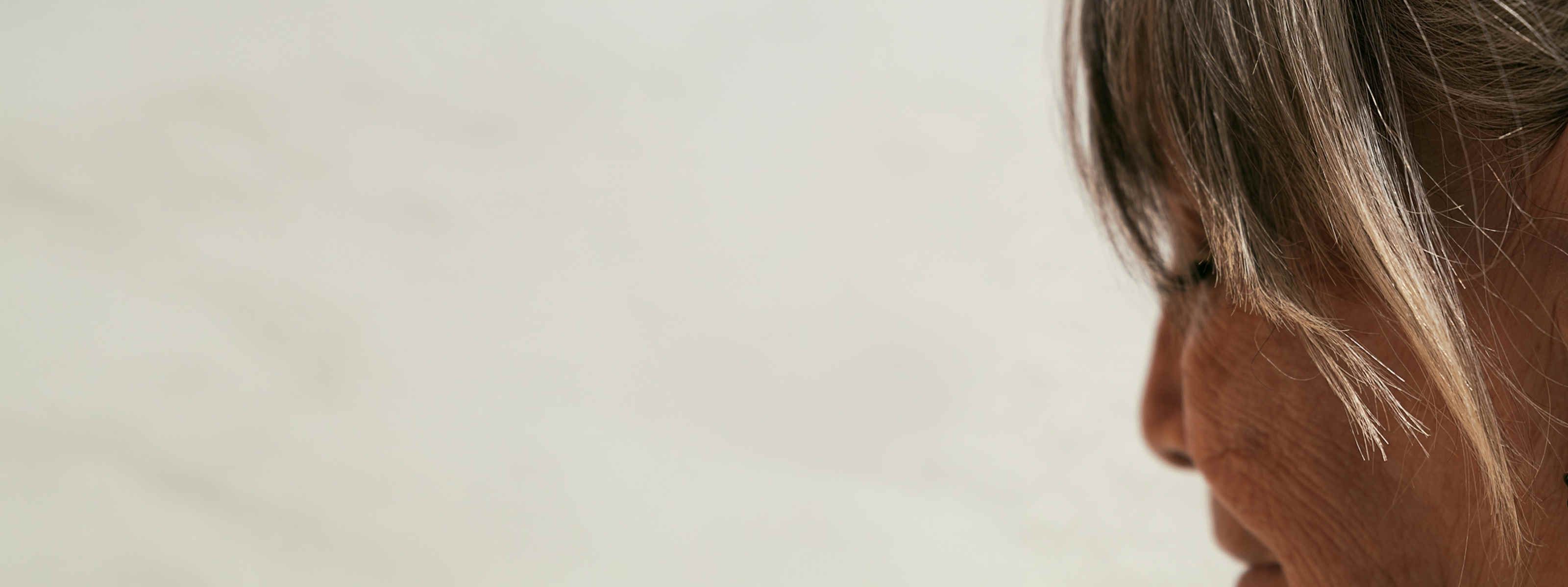 side view of a woman's face and hair in front of a white background