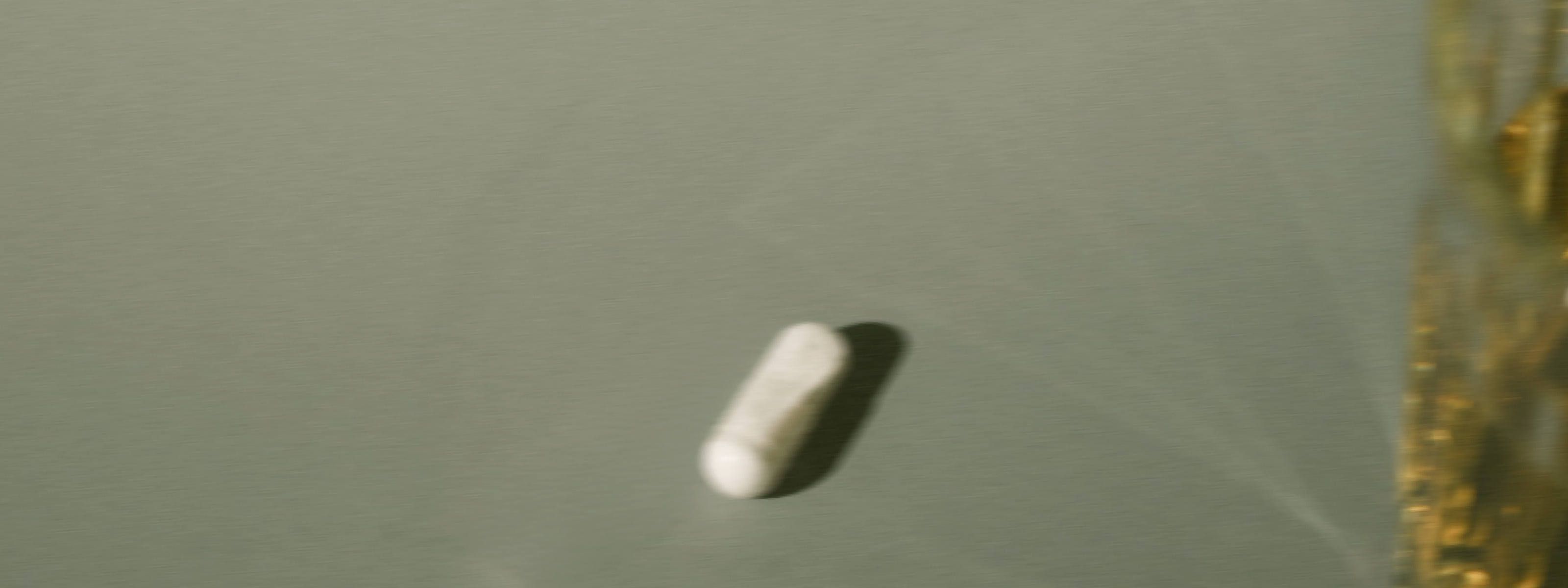 image of a white blurry pill in front of a mossy green background