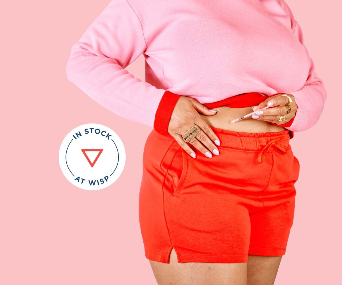 A woman wearing red shorts and a pink sweater injects GLP-1 weight loss medication to her stomach