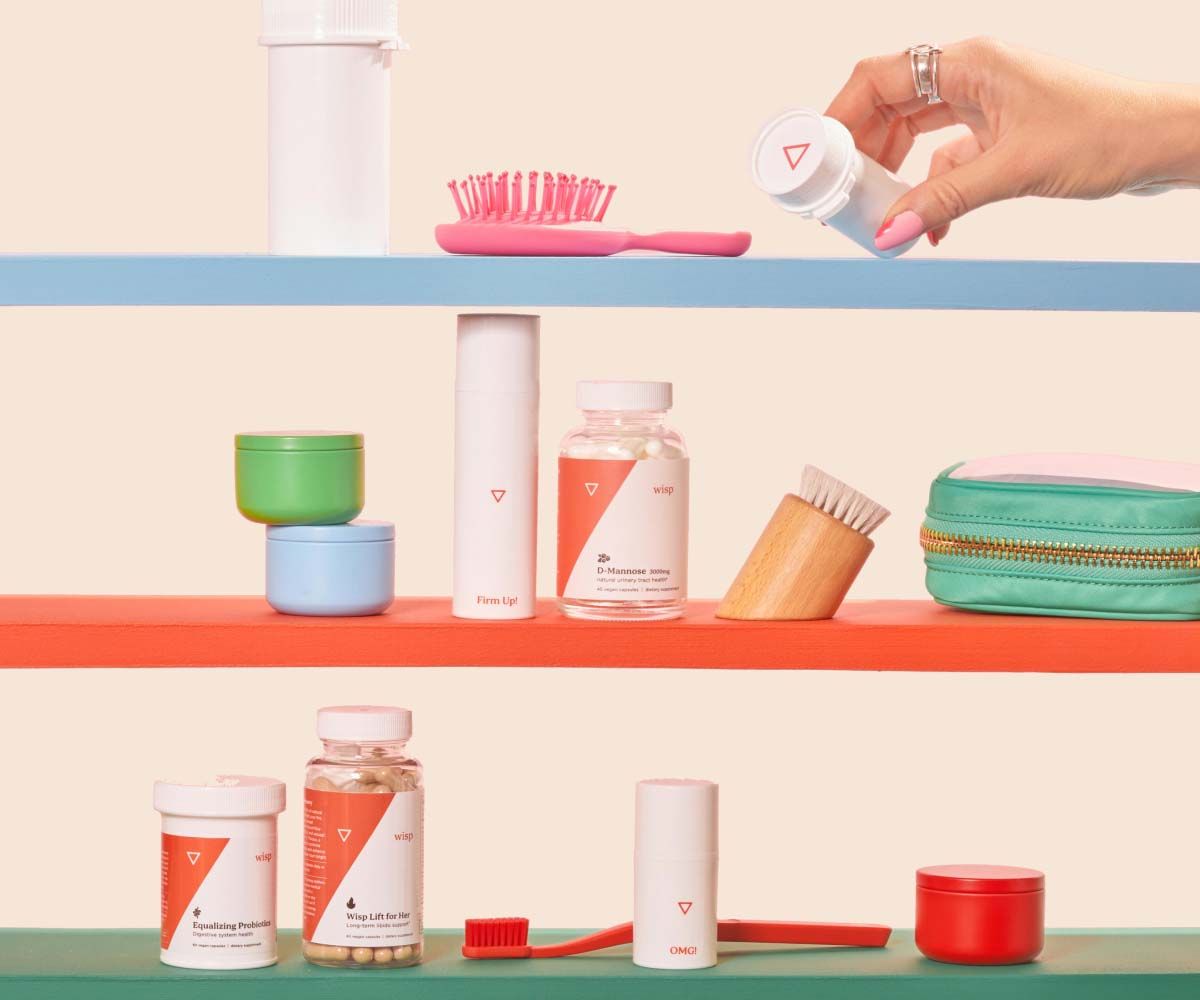 A variety of Wisp products on 3 colorful shelves with a purple toothbrush, a purple hairbrush, and two bars of soap in front of a cream background