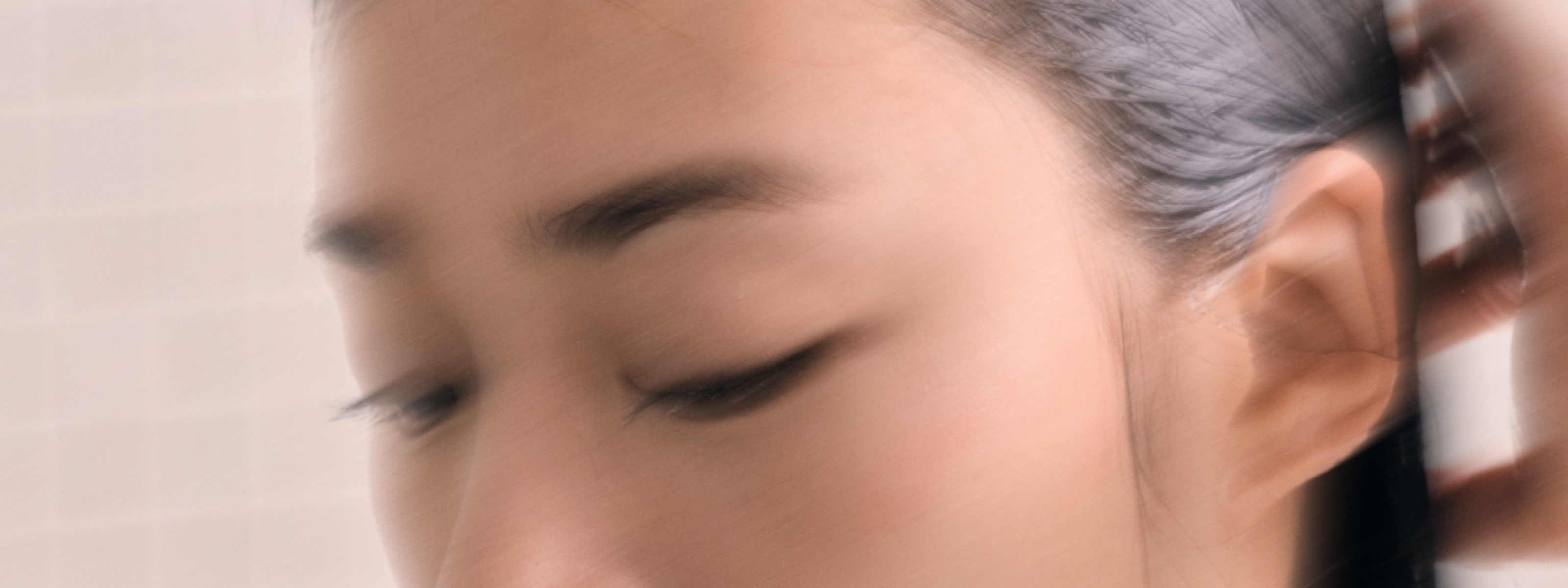 image of woman with her hand combing through her wet hair in the shower