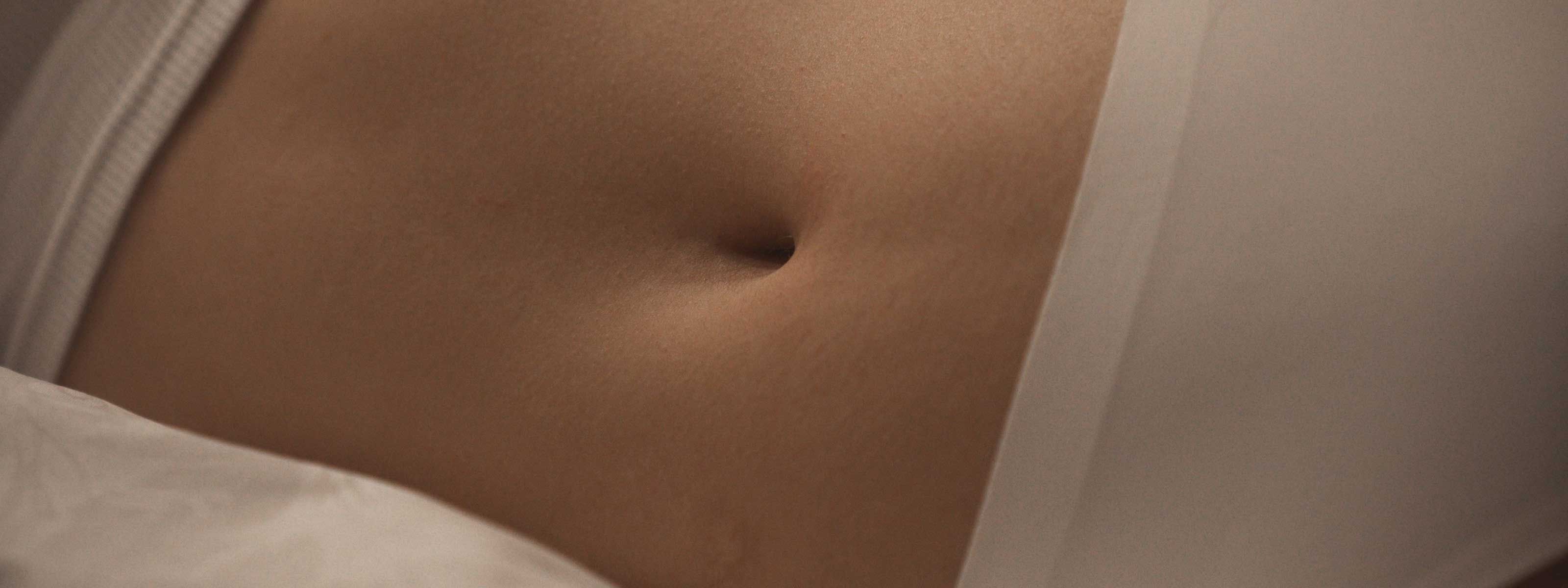 A close up of a woman's abdomen while laying in bed