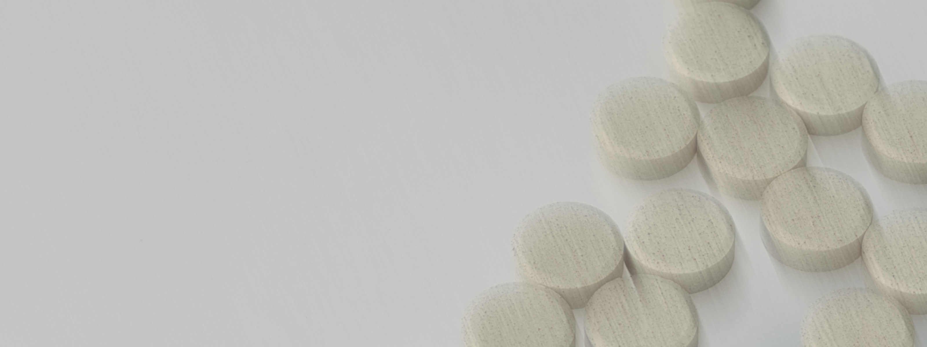 scattered white pills in front of a white background