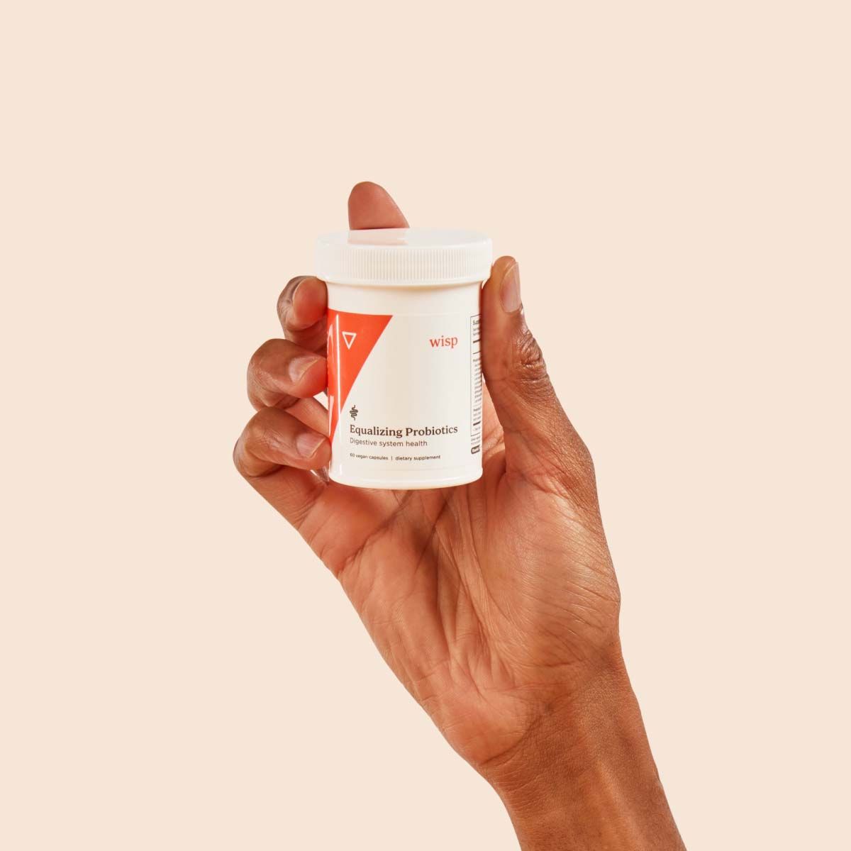 A person's hand holding Wisp Equalizing Probiotics in front of a cream background