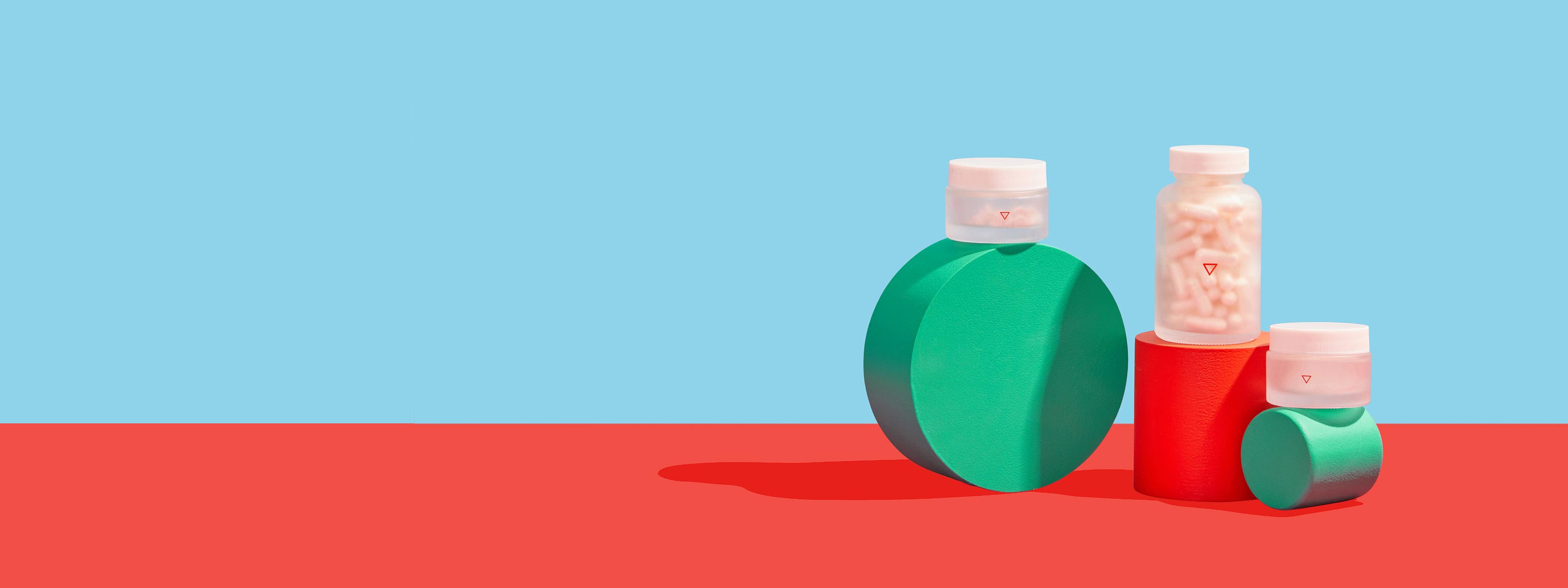 Wisp pill bottles sit on colorful geometric shapes with a red and blue background