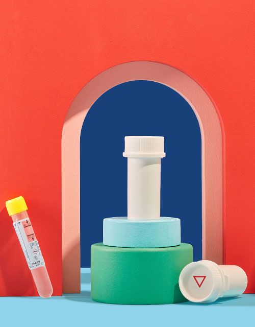 Wisp diagnostic test tubes and pill bottles balanced on colorful abstract shapes on a blue surface with a red background