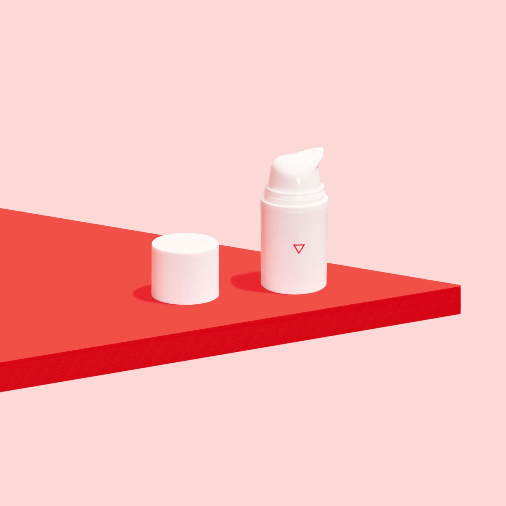 A bottle of Wisp Hydrocortisone Cream on a red surface with a pink background