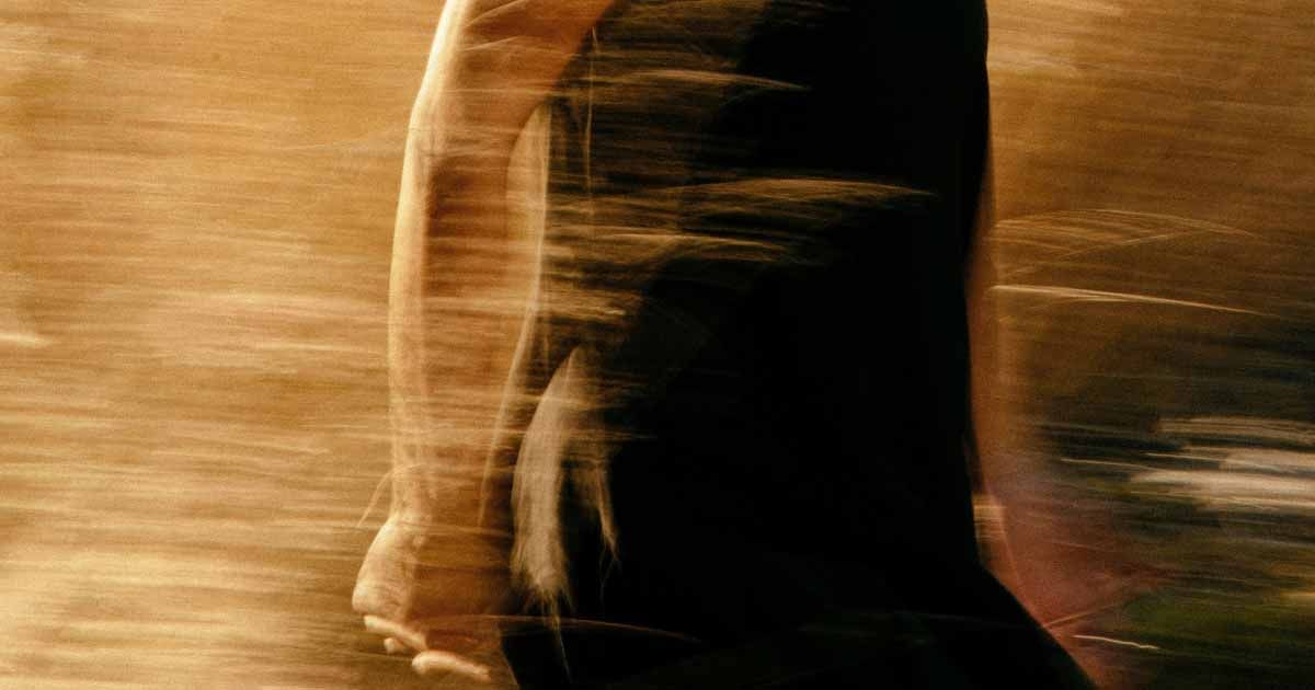 Motion-blurred figure walking through tall grass or a field