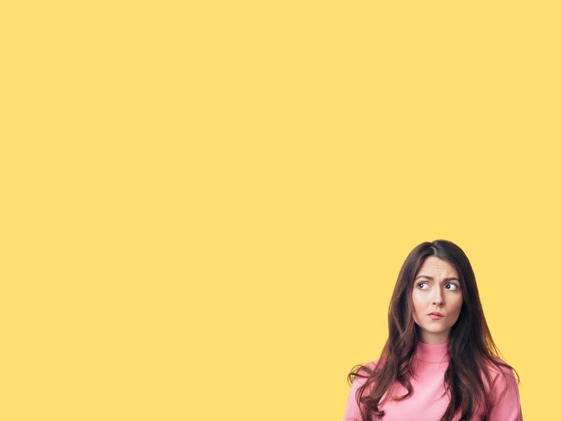 A woman with brown hair wearing a pink shirt has a confused expression in front of a yellow background