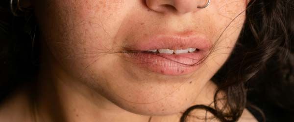 A close up of a woman with brown hair and a nose piercing