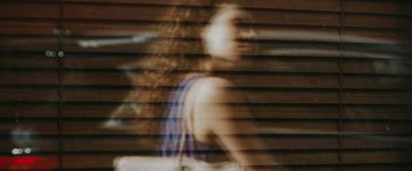A woman with curly hair carrying a tote in the city with motion blur