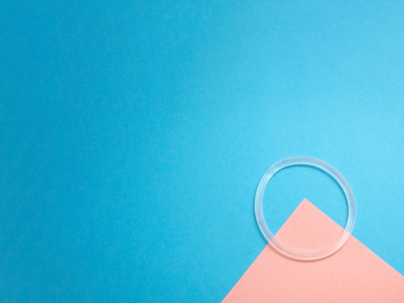 Nuvaring the vaginal birth control ring sitting on a pink and blue geometric background