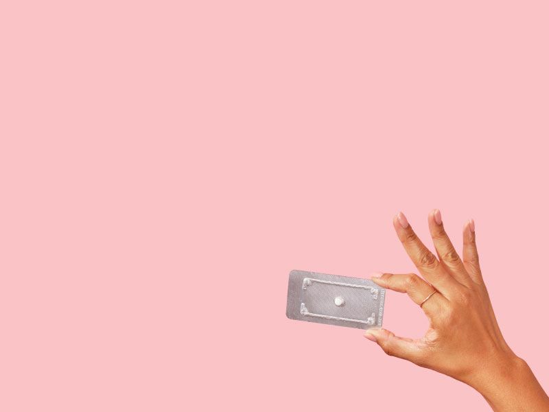 Woman's hand holding a Plan B packet with a pink background