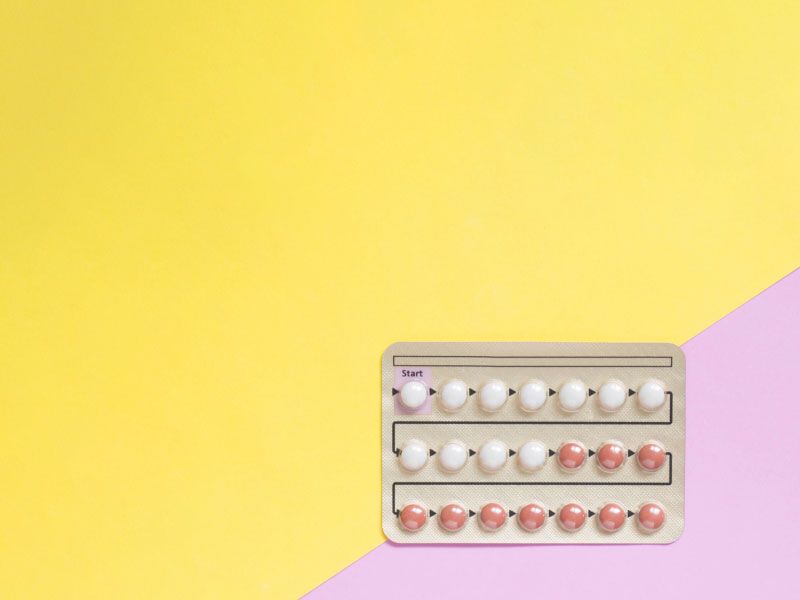 A birth control packet on a yellow and pink background