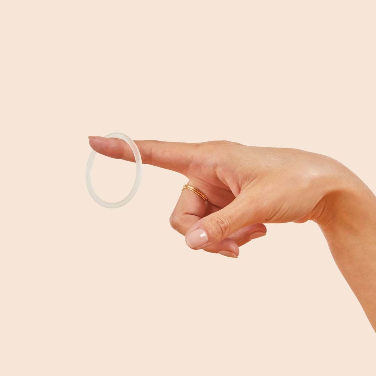 A person's hand holding Nuvaring with a cream background