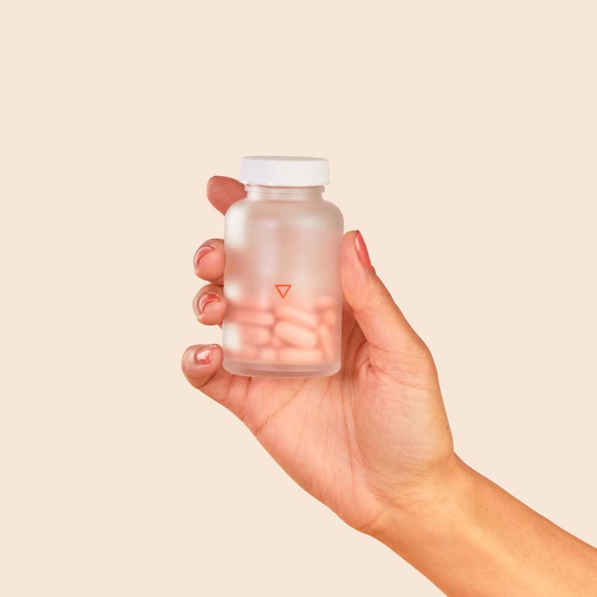 A woman's hand holding Wisp Prenatal Vitamins in front of a cream background