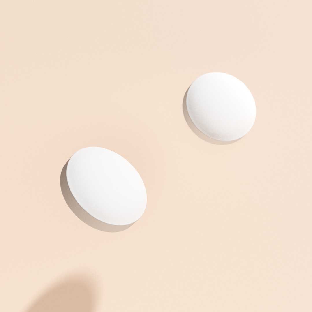 Plan B emergency contraception pills floating above a cream surface