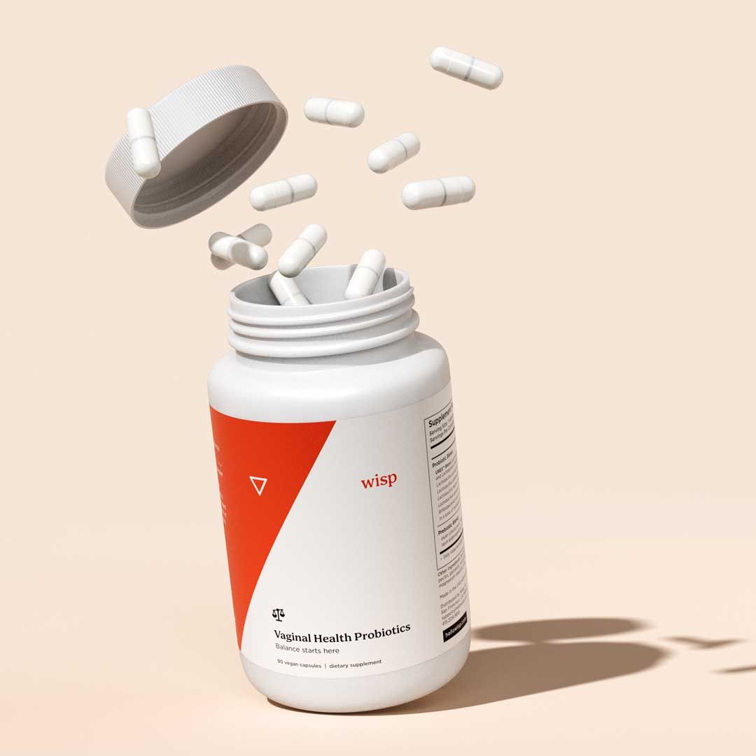 Wisp Vagina Probiotics on a cream surface with pills floating outside the bottle