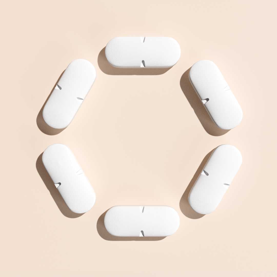 White pills arranged in a circle on a cream surface