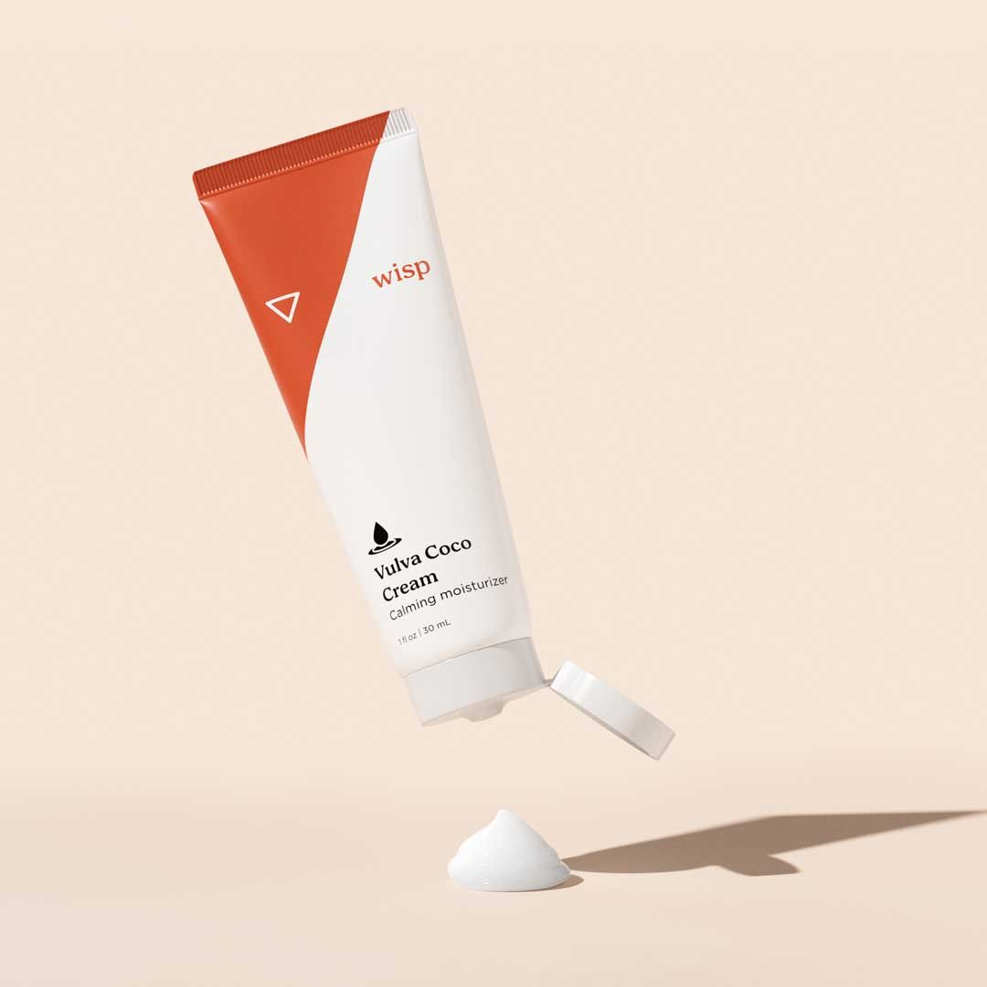 A bottle of Wisp Vulva Coco Cream with a dollop of cream on a beige surface