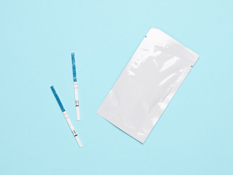 Two test strips and white packet on light blue background