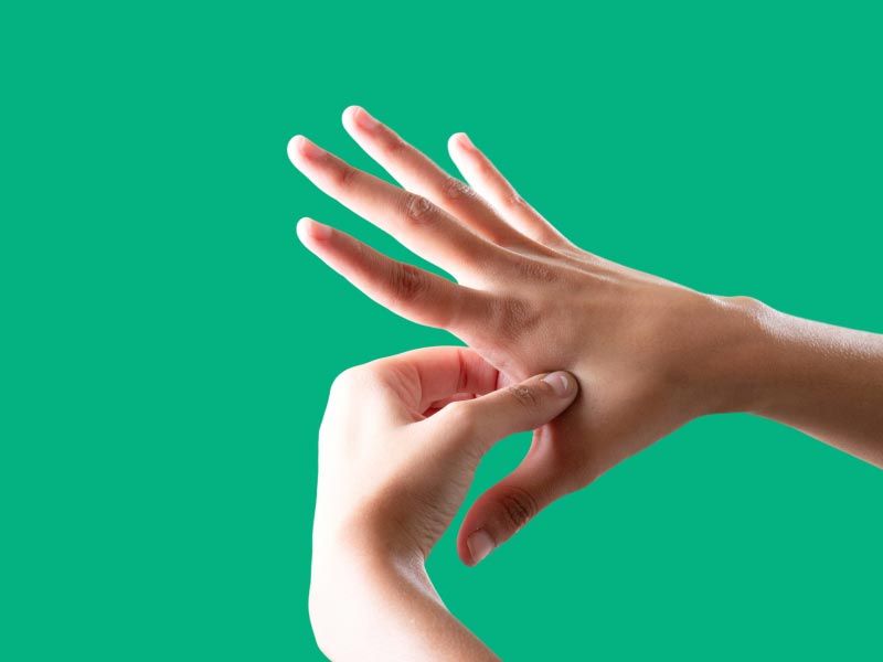 A person's hands applying pressure on a pressure point in front of a green background